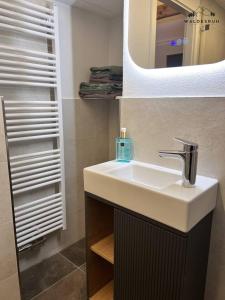 a bathroom with a white sink and a mirror at Waldesruh in Grünenbach +26 photos