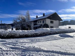 a snow covered yard with a house in the background at Waldesruh in Grünenbach