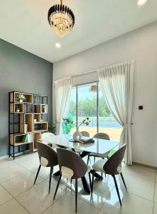 a dining room with a table and chairs and a large window at Jinta House Cherating in Kampong Baharu