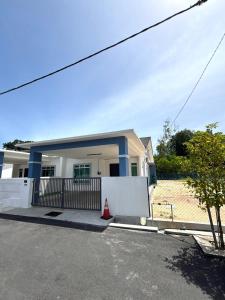 a house with a white fence in front of it at Jinta House Cherating in Kampong Baharu