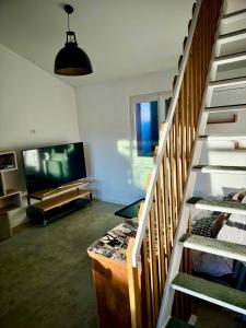 a living room with a staircase and a television at Grand studio avec terrasse in Saint-Marcel-lès-Valence