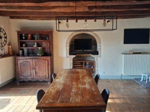 a dining room with a wooden table and a tv at maison d'hôtes in Rouffiac