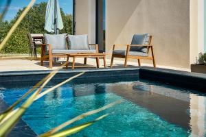 a swimming pool with two chairs and an umbrella at Secluded Pool Villa near Castle in Beynac-et-Cazenac