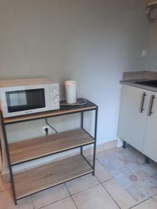 a microwave on a shelf in a kitchen at Logis du Bourg in Puy-lʼÉvêque