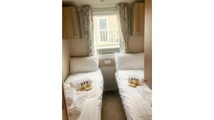 two beds in a small room with a window at Sunset Bay Aberaeron in Aberaeron
