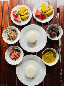 a table topped with white plates with different types of food at Lucky Eagle Nest in Tangalle