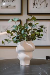 a white vase with a plant in it on a table at JW Canmore ApartHouse in Glasgow