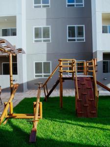 a playground in the grass in front of a building at Apartamento completo com lazer in João Pessoa
