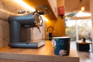 a coffee cup sitting on a counter next to a coffee maker at Charmful Sunset Cabin - Private Hot Tub & Sauna - Beach access in Wapnica +11 photos