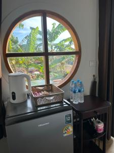 a window with water bottles on top of a refrigerator at Lanta Junli House in Ko Kam Yai