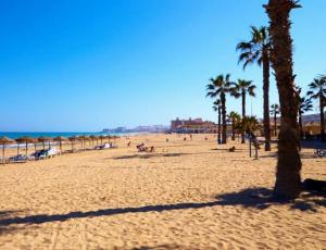 a beach with palm trees and people on it at Smart Space in La Mata