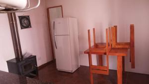 a kitchen with a white refrigerator and two wooden chairs at casitadearminda-II in Villa Las Rosas
