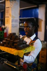 a man is standing in front of a table of food at Dizzy Lizzies Beach House Resort in Kokrobite