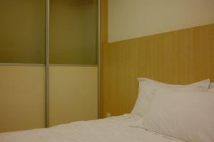 a bedroom with a white bed with a wooden headboard at UrbaNest in Kota Bharu