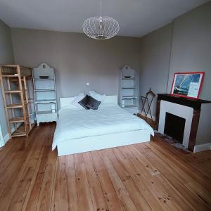 a bedroom with a white bed and a fireplace at Le coin tranquille in Rodez