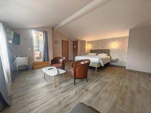 a hotel room with a bed and a table and chairs at Urban Style, Hôtel Le Cheval Noir, Saint-Étienne in Saint-Étienne