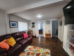 a living room with a brown leather couch at Less is Moore in Thompsonville