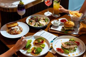 a wooden table with plates of food and drinks at Dusit Suites Hotel Ratchadamri, Bangkok in Bangkok