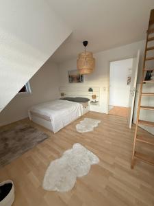 a bedroom with a white bed and a ladder at Gemütliche Galeriewohnung im Grünen in Trappenkamp