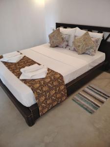 a large bed with white sheets and pillows on it at Charlotte Inn in Kandy