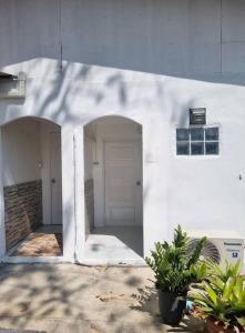 a white building with a door and two potted plants at Atchanin camping room 2 in Ban Samet