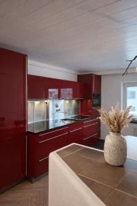 a kitchen with red cabinets and a vase at Stadtappartement Saalfelden in Saalfelden am Steinernen Meer +7 photos