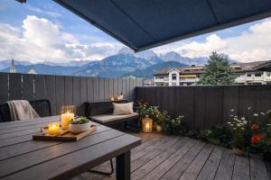 a wooden table on a deck with a view of mountains at Stadtappartement Saalfelden in Saalfelden am Steinernen Meer