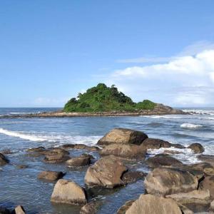 an island in the ocean with rocks in the water at Mar e sol in Itanhaém
