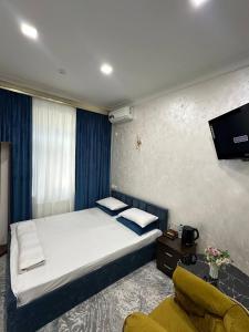 a bedroom with a bed and a tv on the wall at Marvarid Hotel in Ghijduwon
