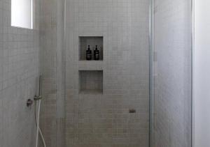 a bathroom with a shower with two bottles on shelves at The Village by WPS in Pollonia