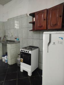 a kitchen with a stove and a white refrigerator at Casa 2 quartos em frente a praia na cidade mística de colares a 96 quilômetros de Belém do Pará in Colares