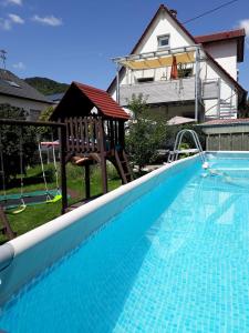 a large swimming pool with a swing and a playground at Ferienwohnung Neifer in Bad Überkingen