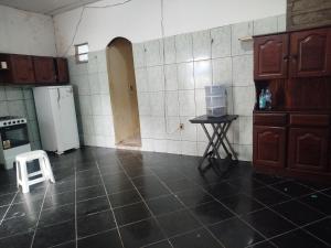 a kitchen with a white refrigerator and a stool at Casa 2 quartos em frente a praia na cidade mística de colares a 96 quilômetros de Belém do Pará in Colares +9 photos