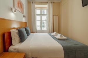 a bedroom with a large white bed with a window at DownTown Guest House in Lisbon