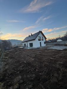 a white house in a field with a dirt yard at Perła pod Śnieżką in Miłków