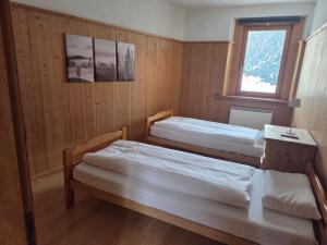 two beds in a room with a window at Chasa Bellavista in Ardez