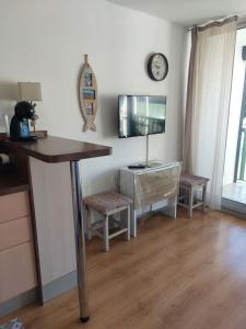 a living room with a desk and a tv on the wall at Le Grand Large in Gruissan