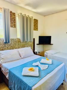 a bedroom with two beds with towels and a tv at Casa Adriê in Itacaré