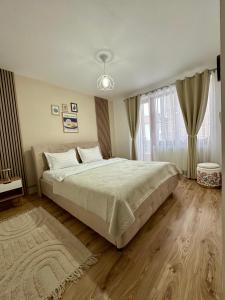 a bedroom with a large bed and a large window at Cozy Apartment D&D in Topliţa
