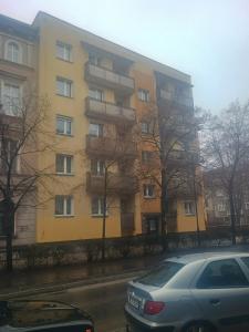 a yellow building with cars parked in front of it at Apartament cisza i spokój in Toruń