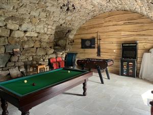 a game room with a pool table and a stone wall at Le gîte du parayre in Lunac