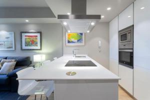 a white kitchen with a sink and a living room at Luxury II in Madrid