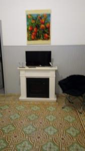 a living room with a fireplace with a painting on the wall at Buonavacanza in Erice