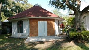 a small building with a white door and a tree at Quinta Corona Hospedaje Familiar in Oaxtepec