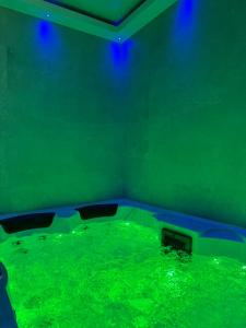a pool of green water in a room with blue lights at Hammam du château in Francheville