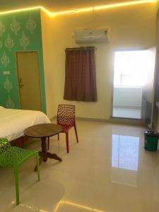 a bedroom with a bed and a table and a window at KH Residency And Lodging in Punganūru