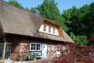 a large wooden house with a thatched roof at Ferienwohnung am Eichenpark, Lüneburger Heide in Egestorf