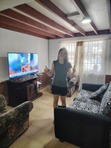 a woman standing in a living room playing a video game at Iquique Backpackers Beach House in Iquique