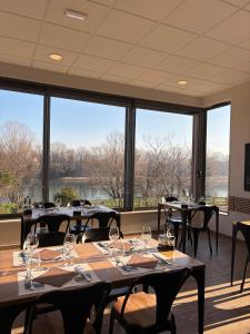 a dining room with tables and chairs and large windows at Les Terrasses du Rhône, Baix in Baix