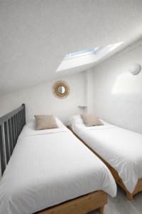two beds in a white room with a skylight at Mazet avec piscine collective in Le Lavandou +12 photos